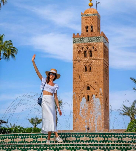 happy woman in front of jemaa el-fna mosque raising her hand