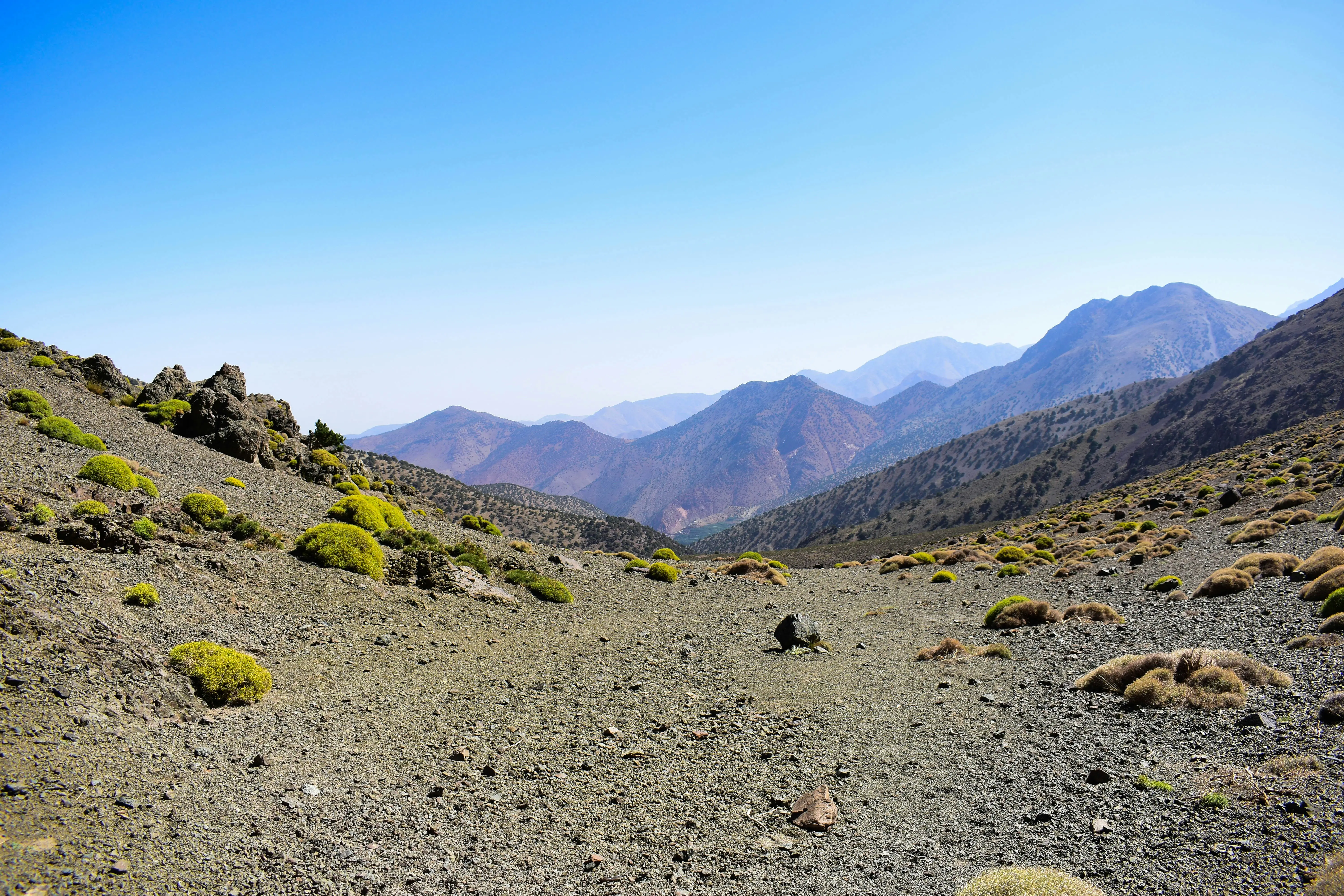 The-image-depicts-a-traditional-Berber-village-with-stone-houses,-nestled-among-lush-terraced-fields-in-the-stunning-Atlas-Mountains.-This-picturesque-scene-highlights-the-local-culture-and-agricultural-practices-of-the-Berbe.webp