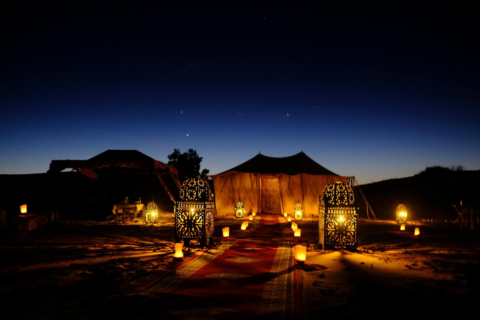 elegant-tents-illuminated-by-traditional-lanterns,-set-against-a-breathtaking-starry-night-sky.-This-enchanting-scene-invites-visitors-to-relax-and-explore-the-wonders-of-Morocco,-offering-an-unforgettable-experience-.jpg