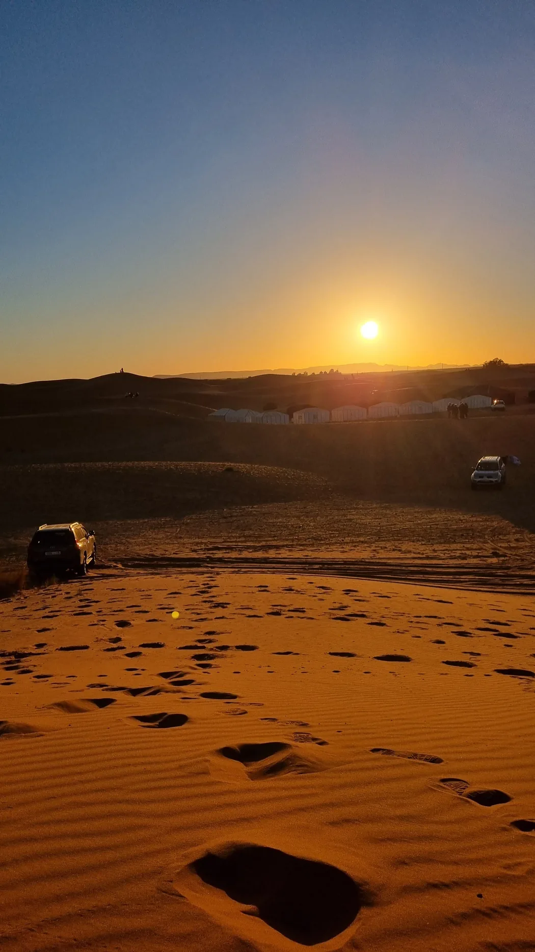 Sunrise over the Erg Chebbi dunes with a desert camp below, Merzouga, Morocco
