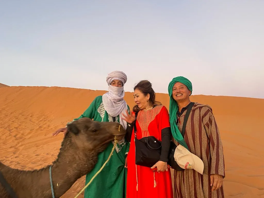 A camel guide leading travelers across the Erg Chebbi dunes at Merzouga