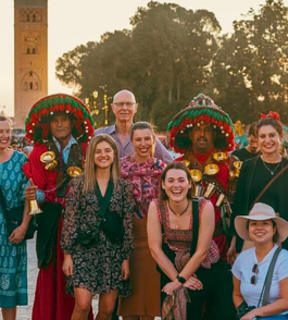 happy group of tourists taking a picture with a local in marrakech in front of jemaa el-fna